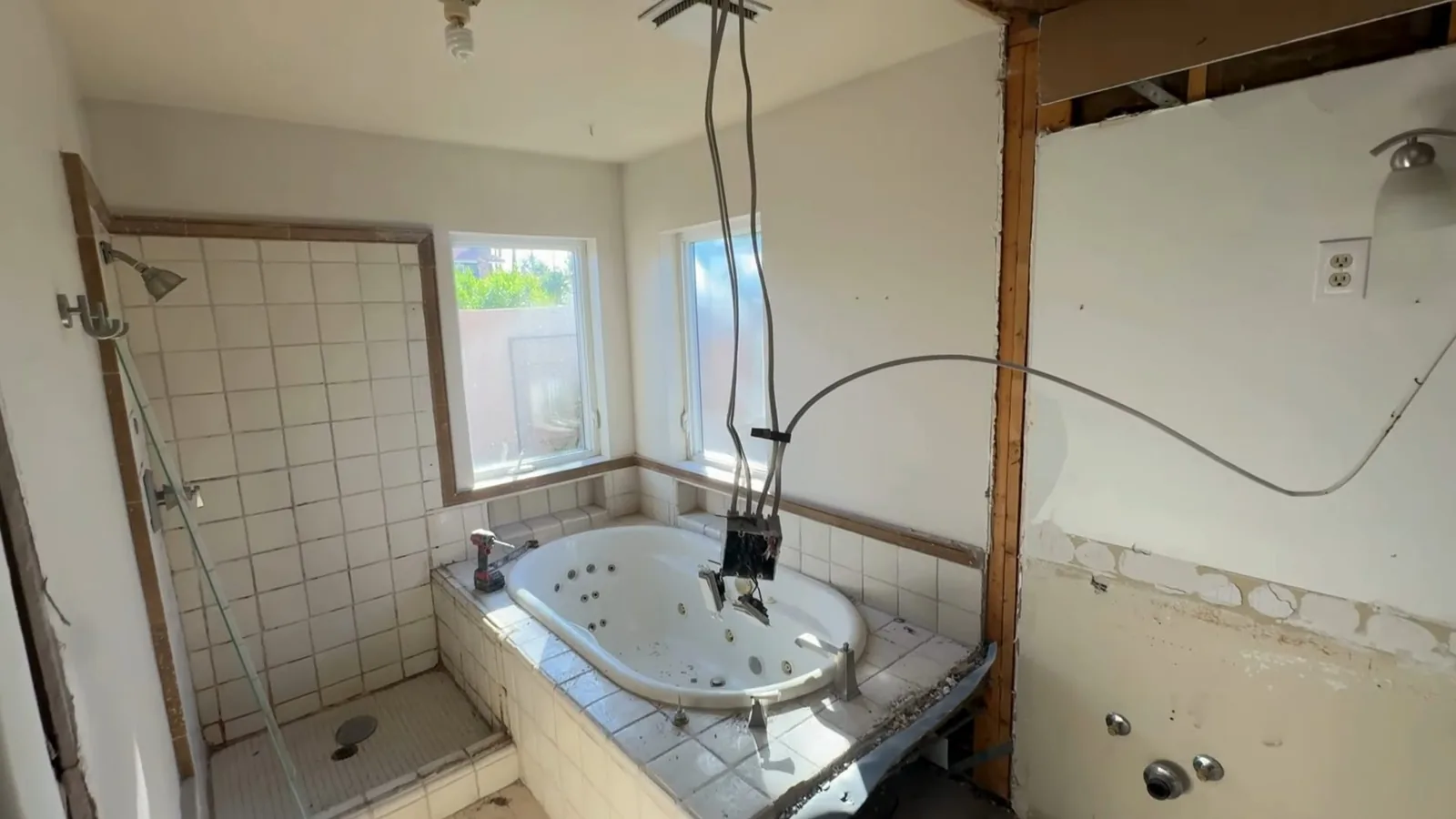 Bathroom with open wall studs, a whirlpool tub and cables hanging from the ceiling.